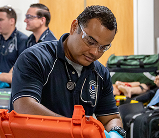 EMT student working in an orange EMT supply kit in a classroom