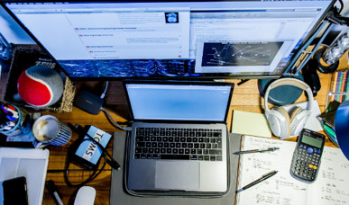 A computer keyboard and monitor sitting on a table with papers and notebooks.