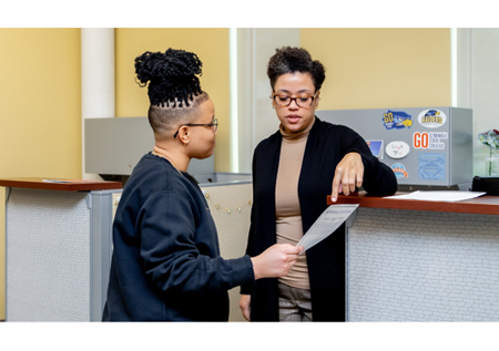 A DSS employee is talking to a student and pointing to a paper in this student's hand