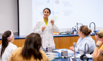 Dr. Amee Mehta giving a lecture to a class in a lab classroom.