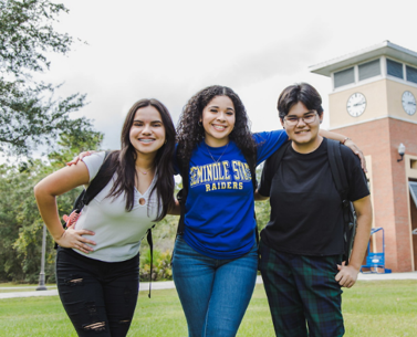 three students standing together in front of the clock tower on the Lee Campus at Oviedo